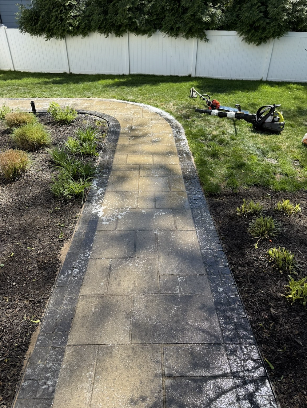 Curved paver walkway installed between landscaped beds