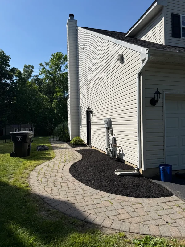 Curved paver walkway beside a house and mulched planting bed