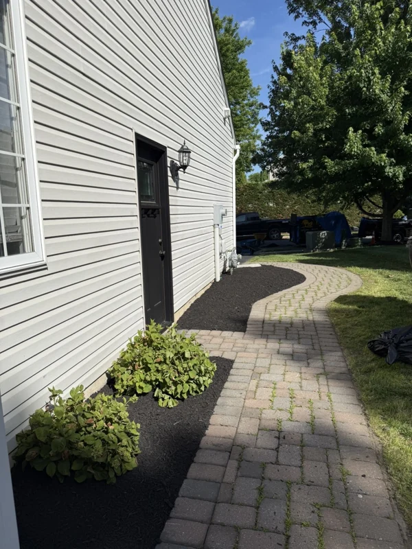 Paver walkway and fresh mulch beds beside a house