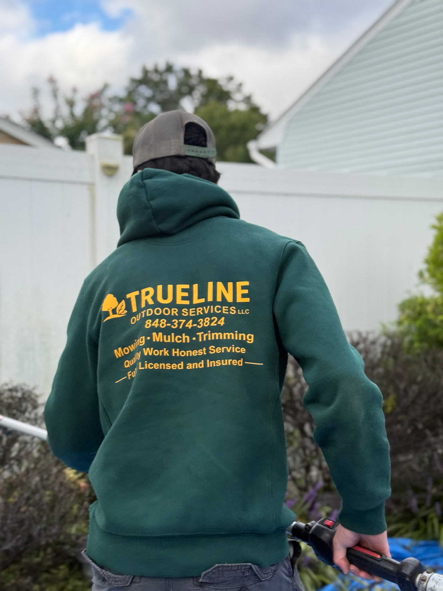 TrueLine Outdoor Services LLC crew member in a company hoodie on a Monmouth County job site